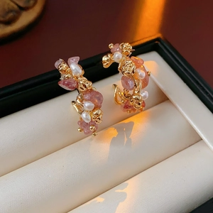 Close-up of gold rose earrings with strawberry quartz and pearls in a jewelry box