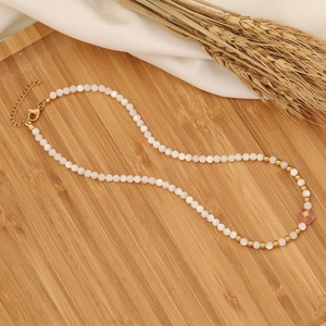 Beaded necklace with white round pearls, pink star pendant and golden clasp on a tray