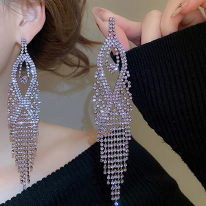 Macro shot of silver needle tassel earrings with sparkling rhinestone geometric teardrops