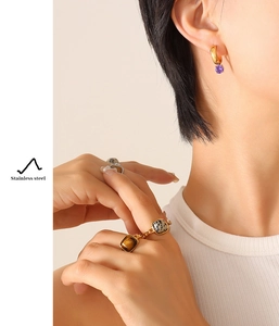 Detail of stainless steel gold ring set with tiger eye stones and purple bead earrings