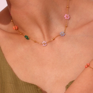 Detail of colorful flower beaded necklace and gold chain on model neck
