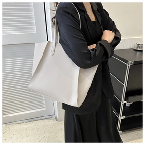 Professional model wearing a large white faux leather tote bag over a black blazer