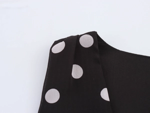 Détail du tissu en mousseline noire à pois blancs sur les larges bretelles de robe