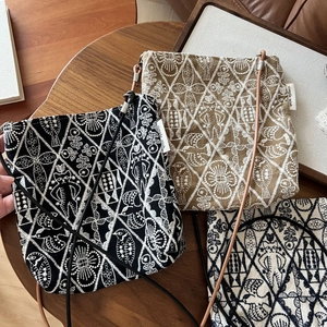 Close-up of ethnic style embroidery on three small canvas crossbody bags in various colors