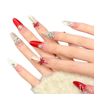 Christmas bow press-on nails with red glitter, snowflake charms and rhinestones
