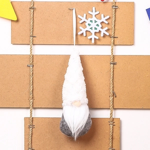 Detail of knitted Christmas gnome ornament with white plush beard on wooden background