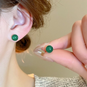 Close-up of polished green agate ball earrings featuring a glossy translucent finish