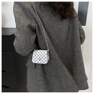Model wearing a white and black geometric crossbody bag with a gold chain strap