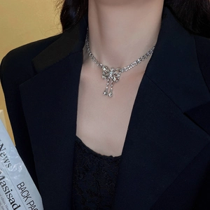 Close-up of sparkling bow tassel necklace with zircons worn by a model on black outfit