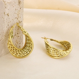 Boucles d'oreilles créoles torsadées dorées en forme de U sur un tissu en soie doux