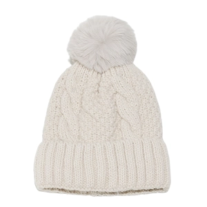 Close-up of beige cable knit beanie with thick texture and fluffy faux fur pom-pom detail