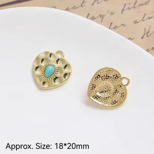Detail of heart-shaped vintage gold charm with turquoise stone and hammered texture