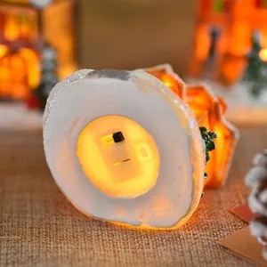 Bottom view of resin Christmas house ornament featuring battery compartment and warm LED light