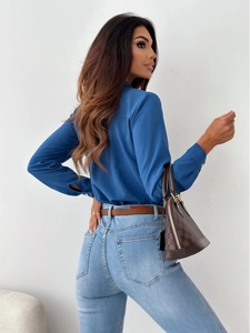 Detail view of a navy blue V-neck blouse paired with light blue jeans from a side-rear angle