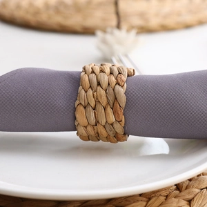 Close-up of woven natural grass napkin ring showing rustic texture on fabric