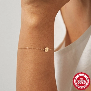Primer plano de la pulsera de plata S925 dorada con un colgante redondo de la letra S