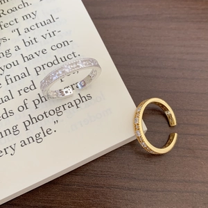 Detailed view of gold and silver adjustable rings with zircon inlay on vintage book