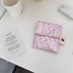 Detailed close-up of a pink heart-quilted satin storage pouch with snap button closure