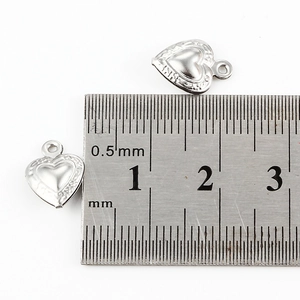 Gepolijste zilveren hartvormige hanger met 10mm afmeting op een stalen liniaal