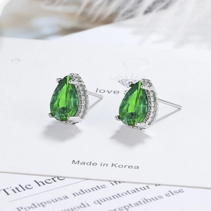 Detailed macro view of pear-cut green zircon stud earrings with silver metal claw settings