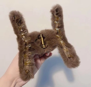 Close-up of brown plush hair claw clip with faux pearl detail and inner plastic structure