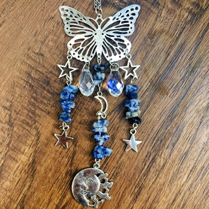 Detailed view of silver butterfly suncatcher with crystal beads on wood background