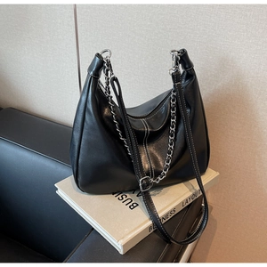 Close-up of black leather hobo bag featuring white stitching and silver metal chain detail