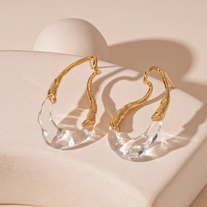 Macro detail of irregular resin drop earrings with gold plating and sleek fluid design