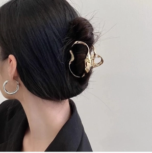 Detailed back view of an irregular gold cloud-shaped hair claw clip on a dark hair bun