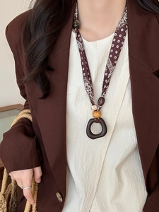 Ethnic fabric necklace with wooden beads and acrylic pendant on model in brown blazer