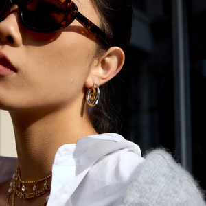 Two-tone interlocking spiral hoop earrings in polished gold and silver on a model