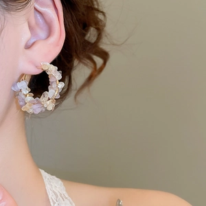 Detail of gold hoop earrings with lilac crystal stones and pearls on model