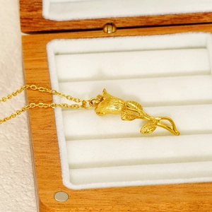 Pendentif rose dorée élégant sur un écrin à bijoux en bois avec doublure blanche