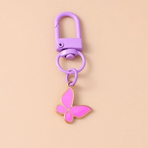 Detail of pink enamel butterfly pendant with purple metal clasp on a floral keychain