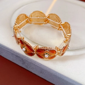 Detailed view of vintage gold bracelet with red enamel and pearls in a jewelry box