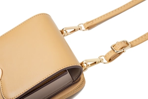Detail of beige PU leather crossbody bag with golden metal buckle and woven strap