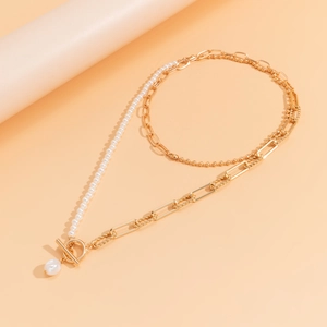 Detail of vintage necklace featuring gold links, beads, and pearls with a stylish OT clasp