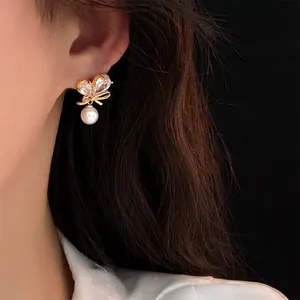 Élégantes boucles d'oreilles nœud plaqué or avec zircon et perle sur un mannequin