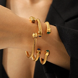 Stack of gold cable bracelets with natural stones on wrist for a minimalist jewelry look