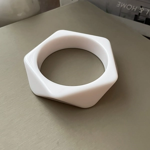 Detailed view of a white geometric resin bangle with hexagonal outer and round inner shape