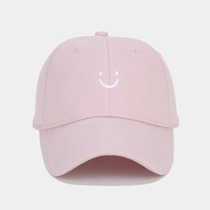 Detailed view of pink cotton twill baseball cap with white embroidered smiley face