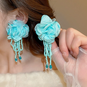 Detail of light blue chiffon flower earring with beaded tassels worn by a model