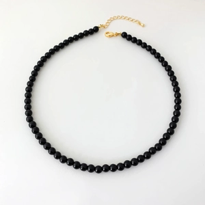 Dettaglio della collana di perle in onice nera con chiusura a moschettone dorata