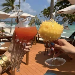 Creative jellyfish and pufferfish glass cocktail goblets on a tropical beach background