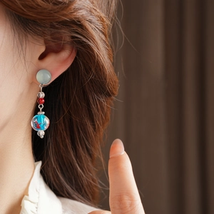 Detail view of handmade starfish style earrings with glass beads worn by a model