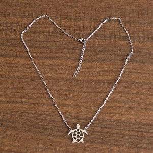 Vue macro d'un collier pendentif tortue argentée sur une chaîne fine en forme de cœur