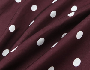 Close-up of wine red polka dot dress fabric showing smooth texture and soft drape