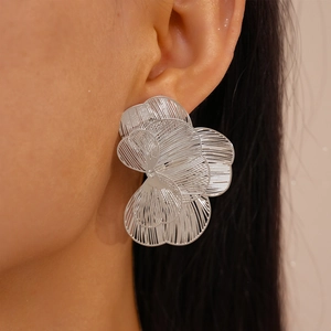 Close-up of a silver hollow-out flower earring showing intricate layered metallic petals