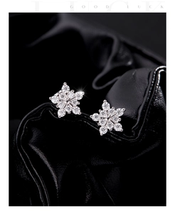 Macro shot of s925 silver snowflake earrings with moissanite on black leather