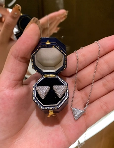 Detailed macro view of silver triangle necklace and earrings set with micro-pave zircons